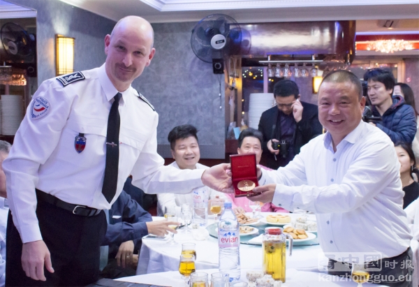 美丽城联合商会姜会长（右）从赫贡局长（左）手中接过奖章。（摄影：林莲怡/看中国）