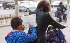 早晨，一位看上去只有一二年级的小学生趴在妈妈后背上看书学习。