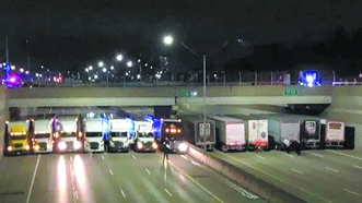 美州际公路上13辆卡车在桥下排成一列，保护桥上一名男子的生命安全。