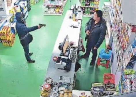 “口罩男”拿“枪”逼超市老板李先生拿5千元钱给他。 (网络图片)