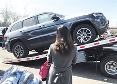 一名女子购买了一辆天津港爆炸受损车辆，正准备用拖车拖走。（网络图片）