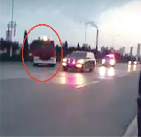 一辆消防车（图中红圈）要调头，却被后面的官方车队逼停。（视频截图）