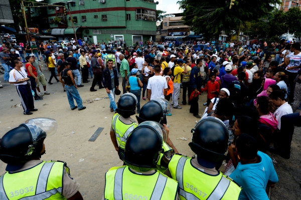 在委内瑞拉首都加拉加斯的一家超市外，人们在等待着购买日常用品，而警察则负责保卫。（Getty Images）