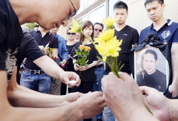 8月14日下午在奥贝维埃市市政府门口为张朝林举行悼念仪式的亲友与同胞。（AFP/Getty Images）