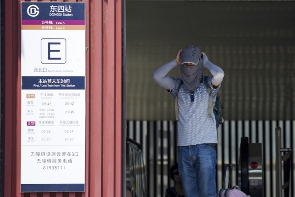 7月12日，北京气温高达35度以上。图为一名男子离开地铁站时，带上太阳面罩以抵挡高温热浪。（Getty Images)