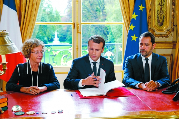 9月22日，马克隆在劳工部长佩尼科（Muriel Pénicaud）（左）和政府发言人卡斯塔纳（Christophe Castaner）（右）陪同下签署劳工法改