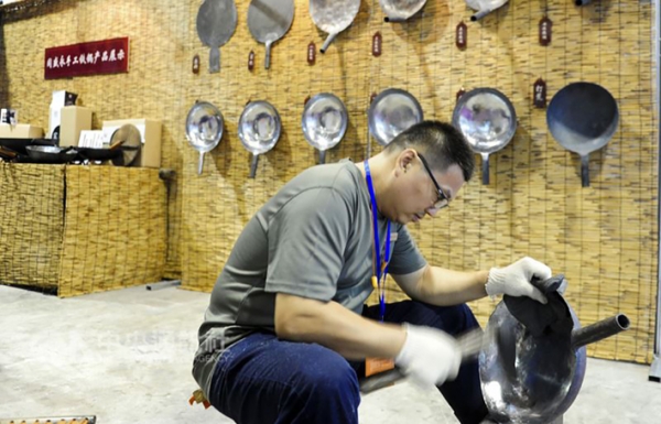 图为2016年山东博览会上，章丘铁匠展示传统技艺造锅。（中央社）