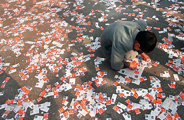 在被扔掉的彩票形成的“海洋”中，一名彩民希望意外发现一张被漏掉的中奖票。（AFP/Getty Images） 