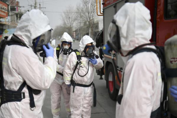 2021年1月15日，穿着防护服的人员正准备在城区的一条街道上喷洒消毒剂。（STR/CNS/AFP via Getty Image）