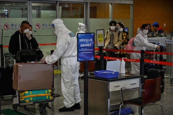 图为2020年3月18日，戴着口罩的乘客抵达上海浦东国际机场（图片来源：HECTOR RETAMAL/AFP via Getty Images）