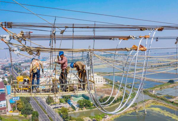 2021年9月27日，工人在江苏省无锡市的高压直流输电线路上工作。（STR/AFP via Getty Images）