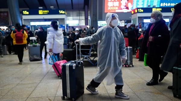 2023年1月12日，一名穿着雨衣的孩子在北京火车站拉着行李。（图片来源：WANG ZHAO/AFP via Getty Images）