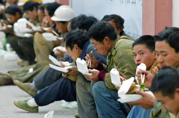 来自西南省份四川的农民工在上海一处建筑工地附近吃午饭。（图片来源：LIU JIN/Getty Images）