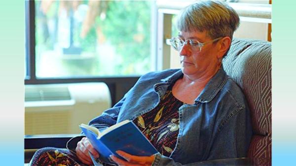 芭芭拉 • 盖伊（Barbara Gay）在阅读英文版《转法轮》。（图片来源：视频截图）