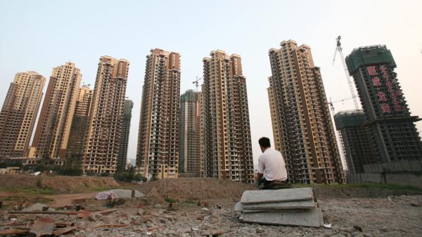 一民众坐在一排还未完工的楼房前。（Getty Images）