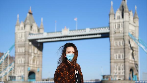 一名戴口罩的女士在英国伦敦塔桥前合影留念。（Alex Davidson/Getty Images）