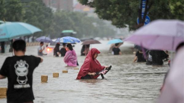 2021年7月20日，中国河南省郑州市人们在暴雨中涉水走过街道。（图片来源:Getty Images）