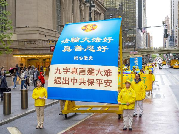 参加游行的法轮功学员推着载有条幅“九字真言避大难 推出中共保平安”的车。（图片来源：摄影/看中国/Leo）